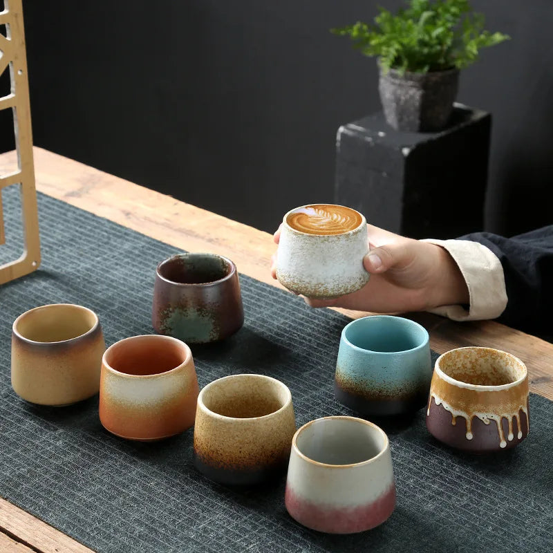 Variety of premium espresso cups in unique designs and colors on a wooden table