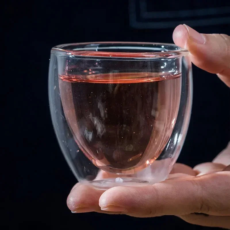 Clear double wall glass coffee mugs held in hand with hot beverage inside by UK Espresso