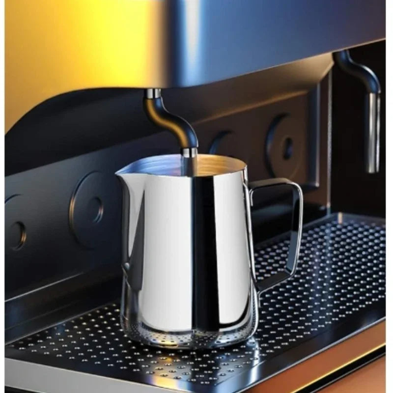 Stainless steel milk frothing jug positioned under an espresso machine for perfect froth preparation